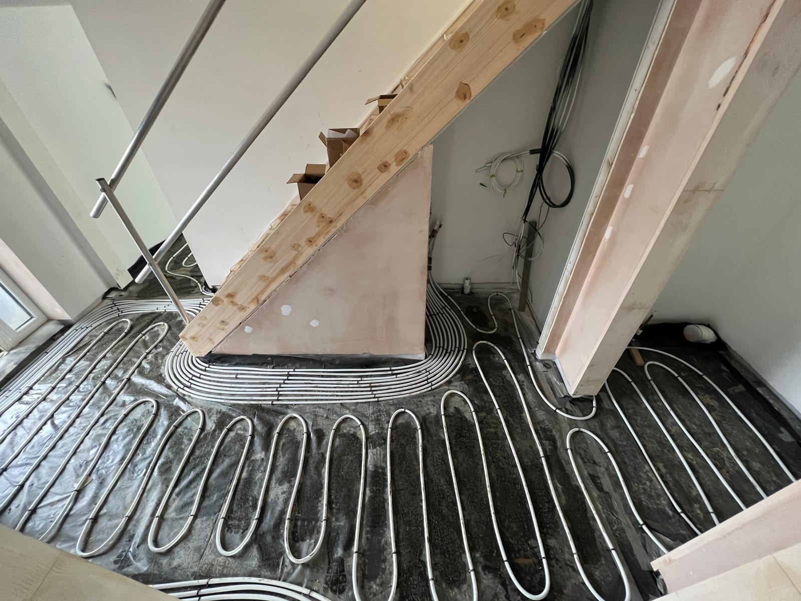 Underfloor heating loops laid around and under a staircase