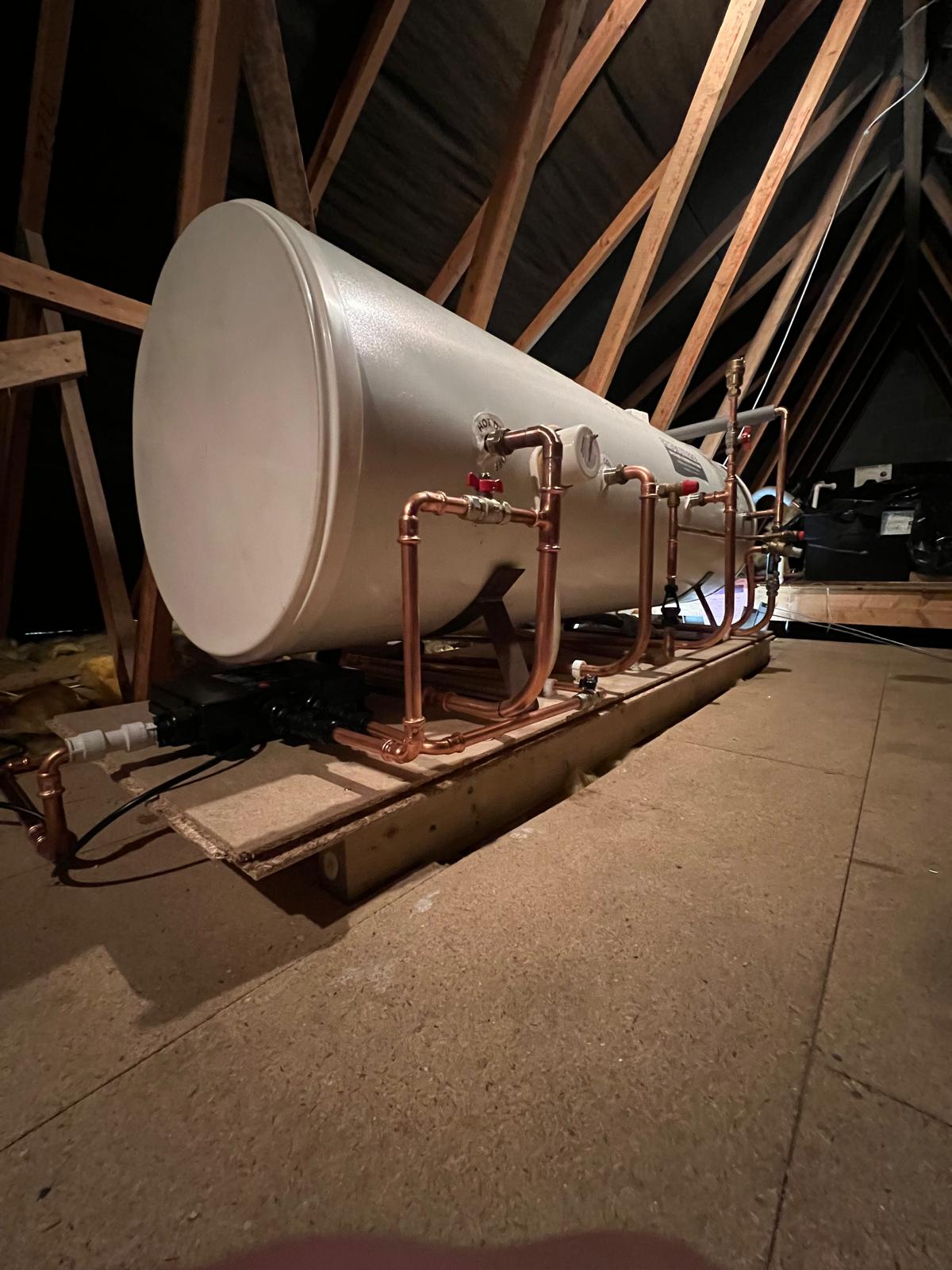 An unvented cylinder installed in a loft, with neat copper pipework